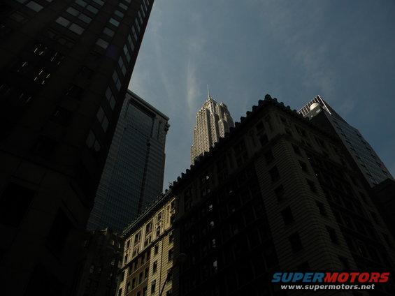 Low angle view of city buildings against a blue sky with wispy clouds