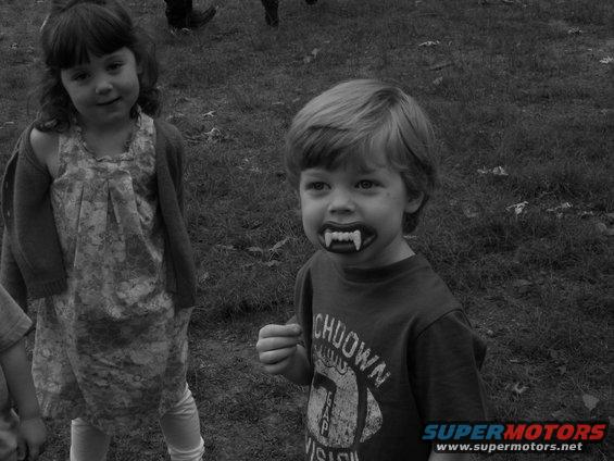 Children in a grassy field, one wearing vampire fangs