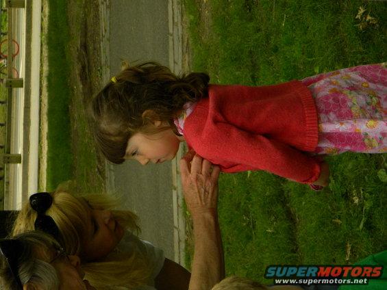 Child in red sweater looking down at people in a park setting