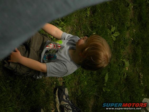 Kid lying on grass, wearing a t-shirt with graphics