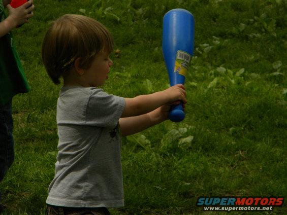 Kid holding a blue toy bat outdoors