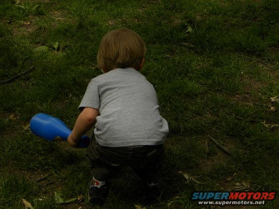 Child holding blue toy in grassy area