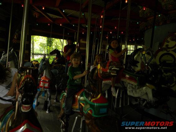 Carousel horses with children riding, Supermotors.net logo visible