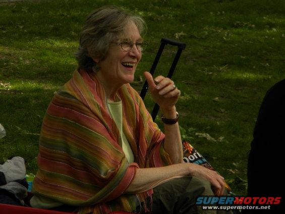 Woman with glasses and colorful shawl laughing outdoors