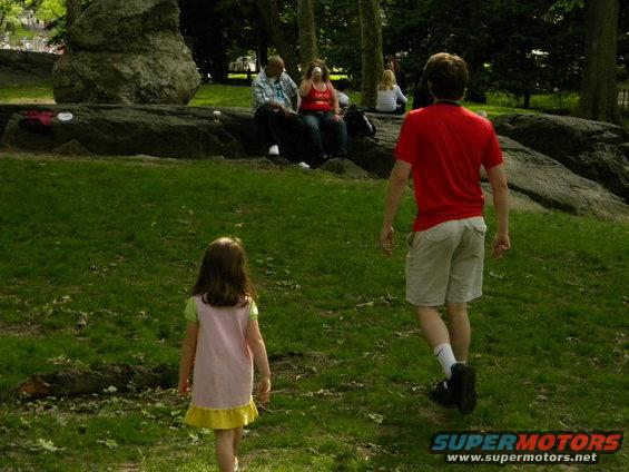 People relaxing in a park, with a young girl and a man walking away from the camera