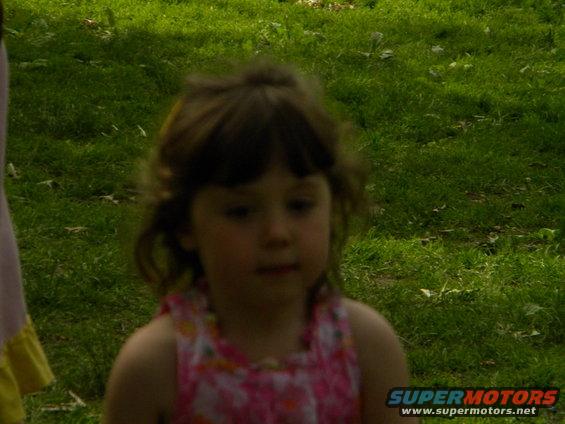young girl in a pink floral dress standing in grass