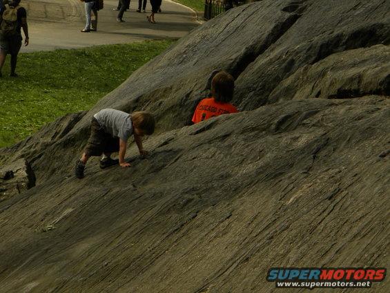 Children climbing on a rocky incline with people in the background