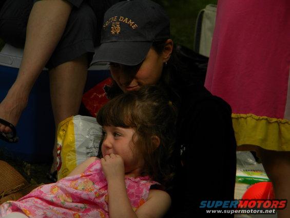 woman in Notre Dame hat looks down at a young girl in a pink dress