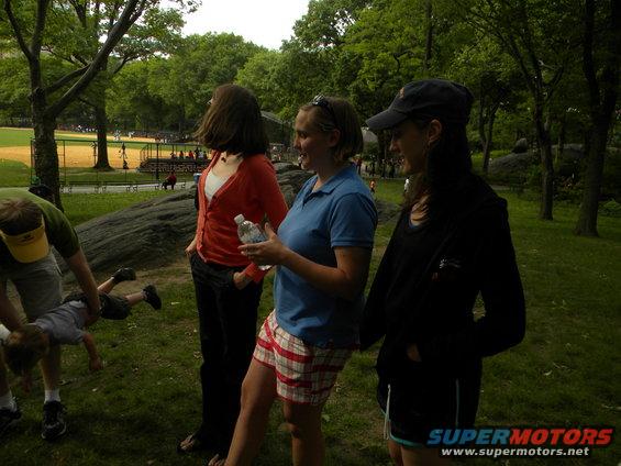 Three women and a man with a child in a park near a baseball field
