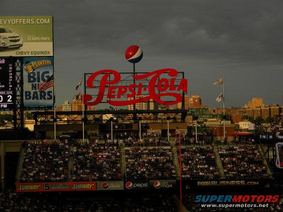 Pepsi-Cola sign above stadium seats. Chevy Equinox ad on left scoreboard