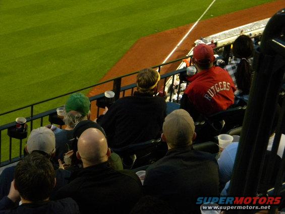 Spectators in stadium seating, one wearing a red jacket with "Rutgers" on the back