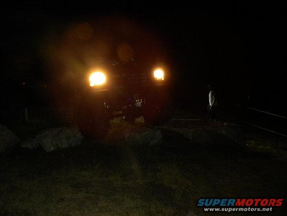 Front view of a dark SUV with headlights on at night
