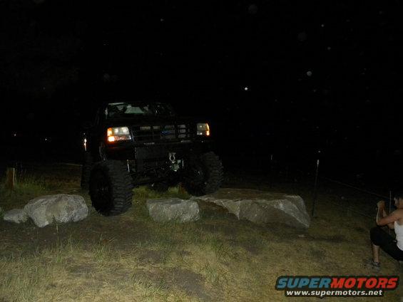 black lifted truck on rocks at night, person watching