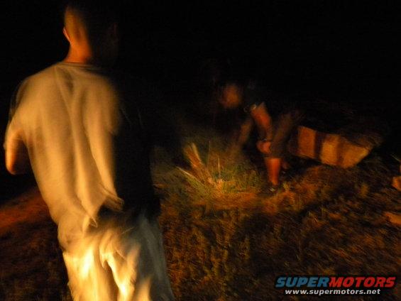 People gathered in grass at night, illuminated by a light source