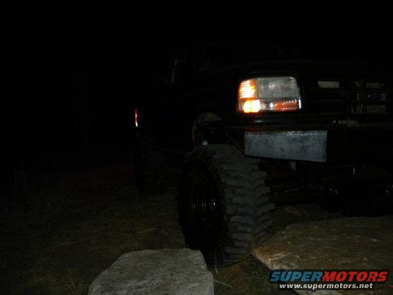 1992 Ford Bronco front corner with headlights on, parked outdoors at night