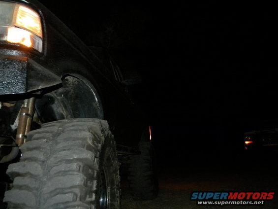 Black 1992 Ford Bronco with large off-road tires, front passenger side visible at night