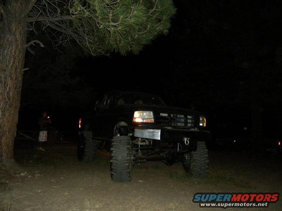 1992 Ford Bronco lifted with large tires, parked at night