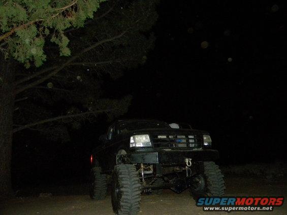 Black 1992 Ford Bronco with lifted suspension and large tires parked at night