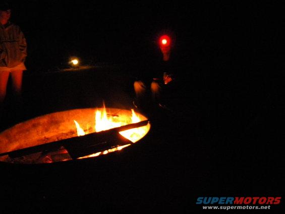Campfire scene at night with people and a red light
