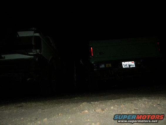 Rear view of two SUVs at night, one green with license plate 5HE5066