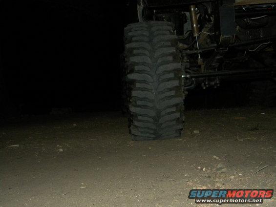 Close-up of a large off-road tire and suspension components against a dark background