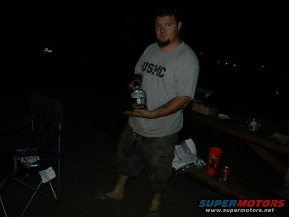 Man in USMC shirt holding a bottle of liquor