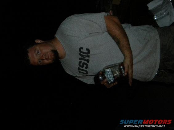 Man wearing a grey USMC t-shirt holds a glass bottle