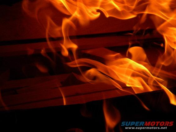 Flames engulfing an unseen object, with intense orange and yellow hues against a dark background
