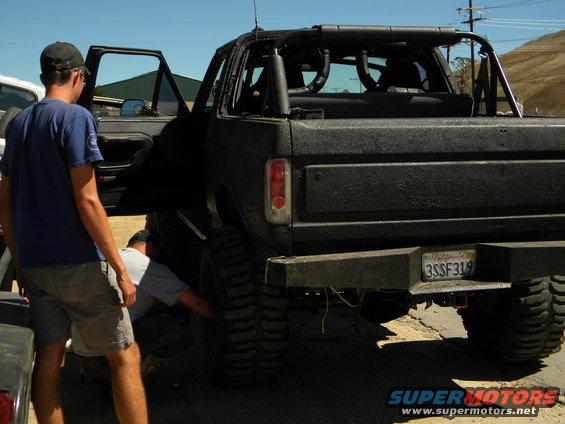 Black SUV rear view with people working on tire. California license plate 3SSF319