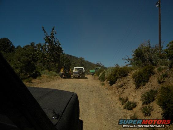 White 1992 Ford Bronco and yellow Jeep on a dirt road