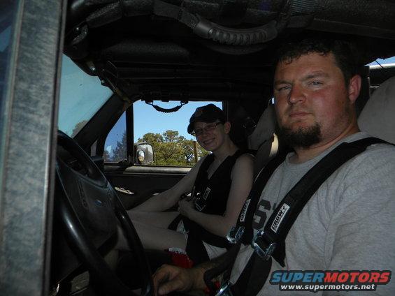 Interior of a modified SUV with two people wearing racing harnesses