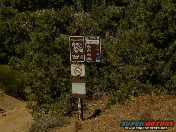 Trail signs with 'Adopt-a-Trail' and 'To HWY 18' information