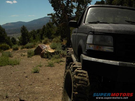1992 Ford Bronco 3q-front view, black with large tires on a dirt road