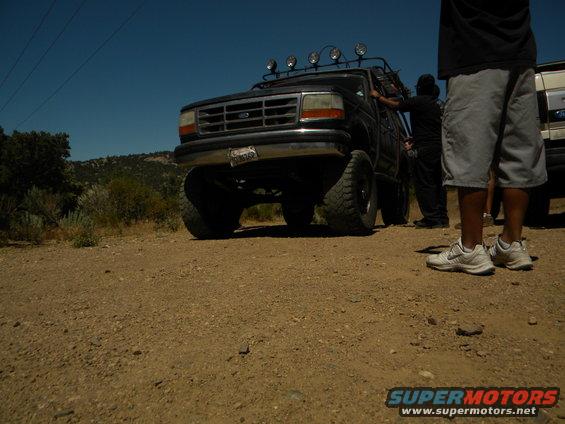 Black 1992 Ford Bronco with roof lights and off-road tires parked on dirt
