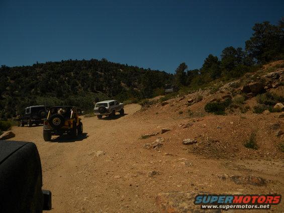White 1992 Ford Bronco on dirt road with other vehicles