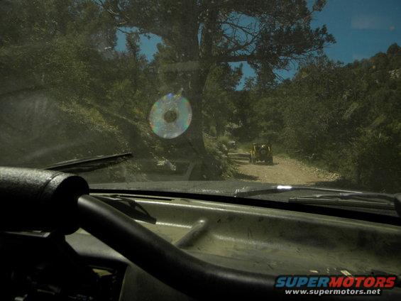 Yellow SUV on a dirt road, seen from inside another vehicle