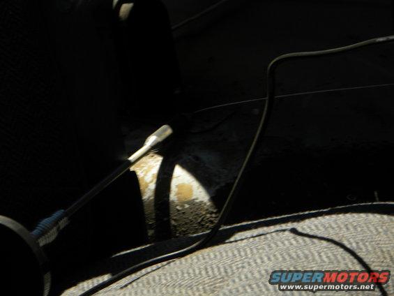 Interior view of a vehicle showing a lever and wires on a textured seat