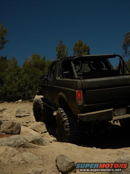Modified black Ford Bronco with large tires on a rocky trail