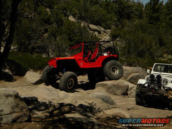 Red off-road jeep with roll cage on rocky terrain