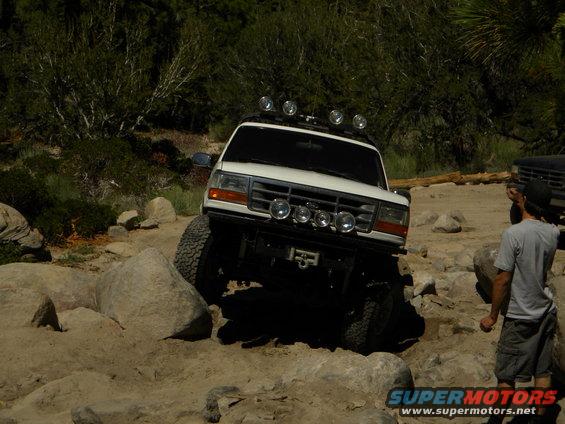1992 Ford Bronco 3q-front view, white, off-roading over rocks