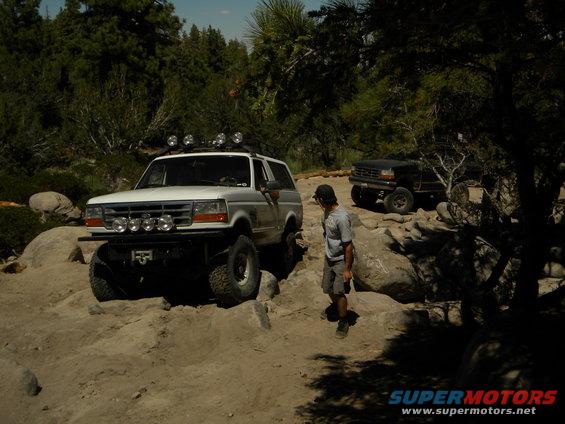 White 1992 Ford Bronco with off-road lights navigating rocky terrain