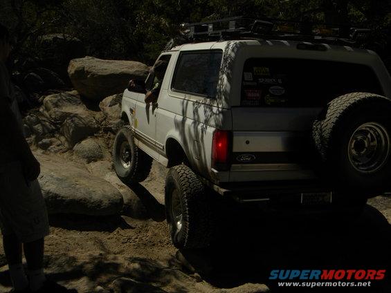 1992 Ford Bronco driving over rocks, spare tire mounted on rear door