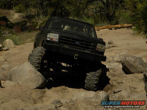 Black 1992 Ford Bronco navigating a rocky trail, front wheels turned