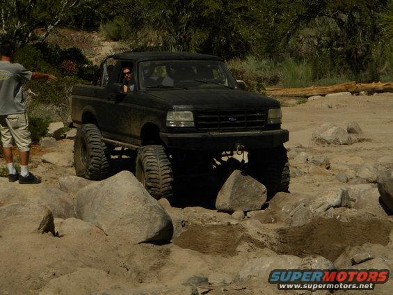 1992 Ford Bronco, front view, black, lifted for off-roading over rocks