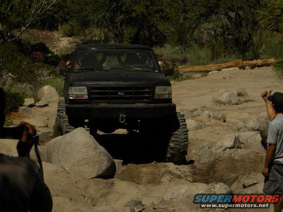 Black 1992 Ford Bronco navigating a rocky trail with people watching