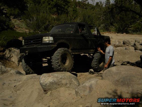 Black 1992 Ford Bronco with large tires navigating rocky terrain