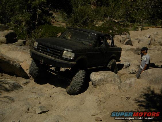 Black 1992 Ford Bronco navigating a rocky trail with large tires