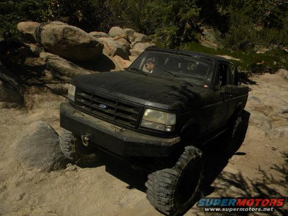 Black truck with aftermarket bumper driving over rocks