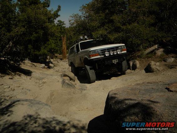 White 1992 Ford Bronco on rocky trail, front bumper with lights, off-road tires