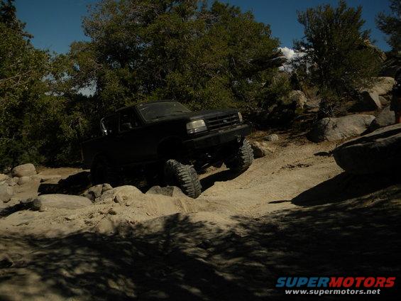 1992 Ford Bronco driving over rocks on a dirt trail